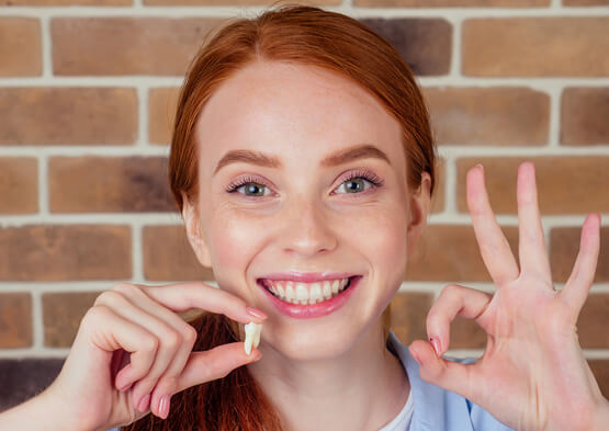 someone smiling and holding their tooth