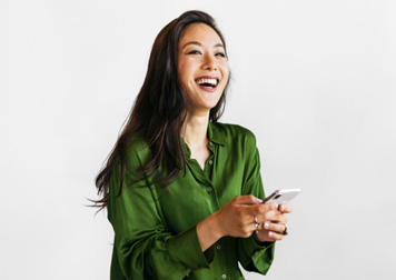 Woman in green shirt smiling holding smartphone