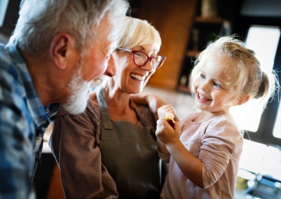 Older couple with grandchild enjoying the benefits of dental implants