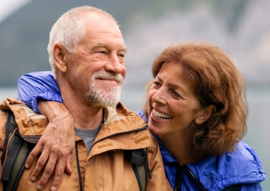 Man and woman smiling after dental implant tooth replacement