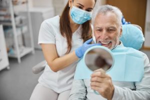 a man happily smiling at his new dental implants after a preliminary procedure