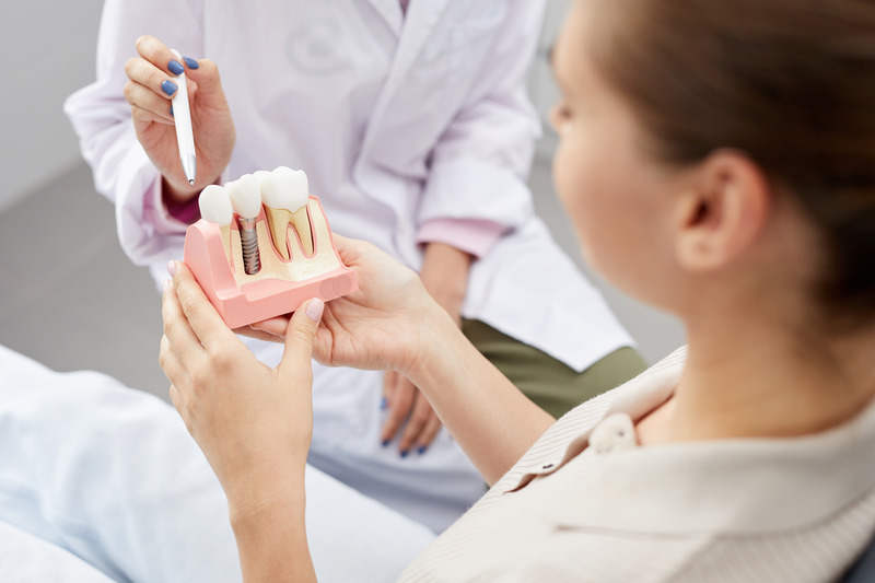 Patient looking at a model of dental implants as periodontist explains